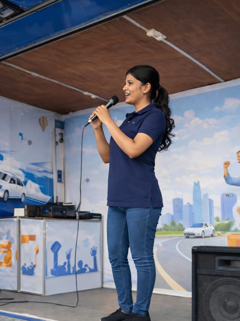 A young woman delivering a speech on a mobile stage at the IASL road show